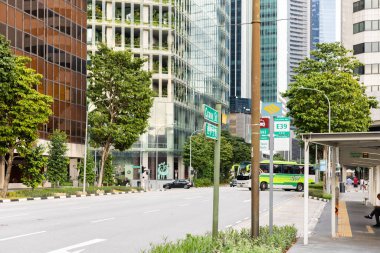 Singapur - 27 Ocak 2026: İnsanlar Singapur 'da bir otobüs durağında otobüs bekliyor. Bir otobüs gelirken uzun binalar cadde boyunca sıralanır. Yoğun yolda arabalar geçer..