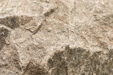 Sahne sert yüzeyi olan bir kayanın yakın görüntüsünü gösteriyor. Işık kayanın üzerine düşer, oyukları ve dokuları renklendirir. Sahne doğal bir açık hava ortamında geçiyor..