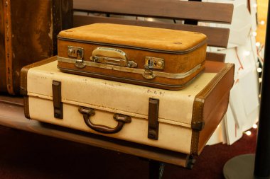 İki eski bavul bir mağazanın içindeki ahşap bir bankta üst üste konur. Ayarlar seyahat tarihi ve tasarım duygusunu yakalar..