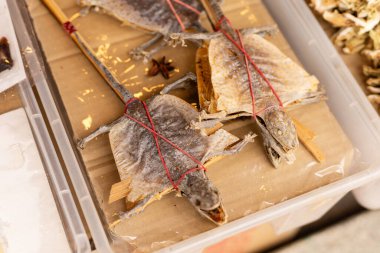 Kurutulmuş kertenkeleler Asya 'da bir pazarda bir masaya dizilir. Kırmızı iplerle bağlanmış ve satışa hazırlar. Müşteriler yakındaki tezgahlara göz atıyor olabilir..