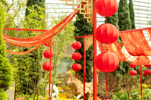 Renkli kumaşlar bahçede akarken parlak kırmızı fenerler binalardan sarkıyor. Etrafı ağaçlarla çevrili. Çeşitli renklerde çiçekler mevcuttur. İnsanlar festivalin tadını çıkarıyor..