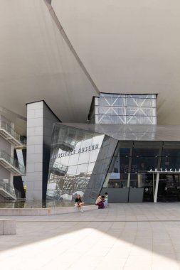 Singapur - 11 Ocak 2026: İnsanlar Singapur Sanat Müzesi 'nin girişine yakın oturuyorlar. Benzersiz bina tasarımı güneş ışığını yansıtıyor. Mekan ziyaretçilerle meşgul..