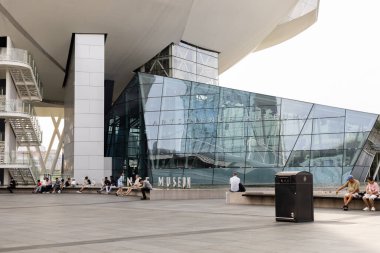 Singapur - 11 Ocak 2026: İnsanlar akşam saatlerinde Singapur 'daki Sanat Bilimleri Müzesi' nin önünde toplanıyorlar. Bazıları banklarda otururken, diğerleri ayakta durup binaya ve çevreye bakıyor..