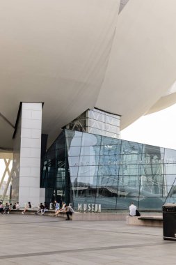Singapur - 11 Ocak 2026: İnsanlar Singapur 'daki Sanat Bilimleri Müzesi yakınlarındaki banklarda rahatlar ve otururlar. Yapı cam ve metalle modern bir tasarıma sahip ve turistler için popüler bir yer..
