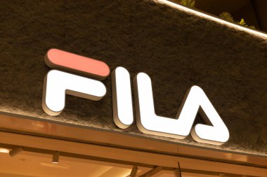 Singapur - 11 Ocak 2026: Singapur 'da gece bir alışveriş merkezinde parlak bir FILA mağaza tabelası sergilenmektedir. Logo dikkat çekiyor, dükkana müşteriler ve ziyaretçiler çekiyor.
