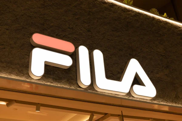 Singapur - 11 Ocak 2026: Singapur 'da gece bir alışveriş merkezinde parlak bir FILA mağaza tabelası sergilenmektedir. Logo dikkat çekiyor, dükkana müşteriler ve ziyaretçiler çekiyor.