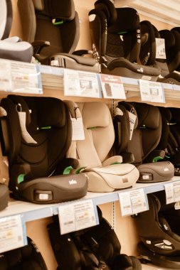 Chemnitz, Almanya - 14 Mart 2026: Bir mağazadaki raflarda farklı araba koltukları düzenlenmiştir. Etiketler her koltuk için bilgi ve fiyat sağlıyor. Müşteriler çocuk güvenliği seçeneklerini gözden geçirir.
