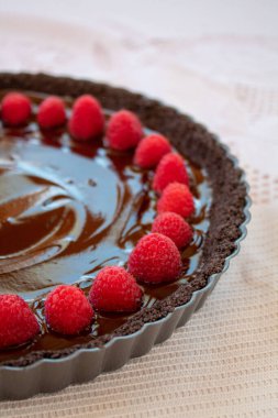 Lezzetli koyu çikolata soslu ve olgun pembe ahududular etrafında