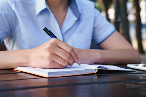 Ragazza è seduta in un caffè e scrivere nel suo taccuino — Foto Stock