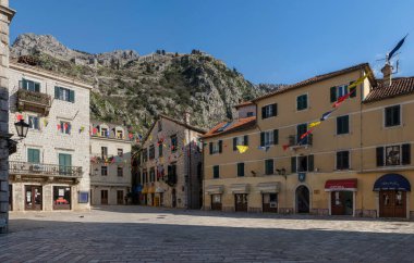 Eski Kotor Kasabası 'nın Panorama' sı, güneşli bir bahar gününde kaldırımlı geleneksel Balkan mimari tarzında butikleri ve kafeleri olan antik bir meydan. Dağlar arka planda görünür.