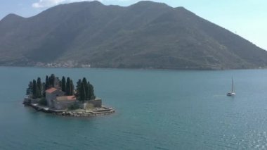 Hava saldırısı, İHA Adriyatik denizinde küçük bir adanın etrafında uçuyor. Bir adada bir manastır, konut binaları ve çam ağaçları var. Yelkenli yat adanın yakınında yüzüyor.