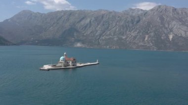 Adriyatik Denizi 'nde küçük bir adaya uçan bir hava saldırısı. Adada beyaz taştan yapılmış bir manastır var. Dağlar arka planda görünür.