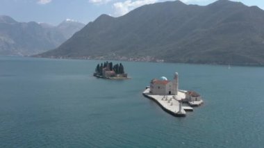 Adriyatik Denizi 'ndeki iki küçük adanın etrafında uçan bir hava atışı. Bir adada beyaz taştan yapılmış bir manastır var, diğerinde ise konut binaları, kilise ve çam ağaçları. 
