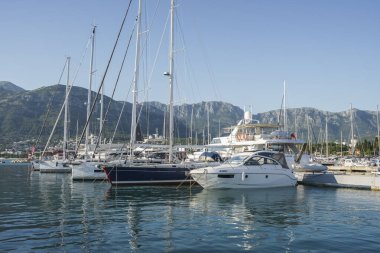 Bar, Karadağ, 18 Haziran 2021: Monthe Town Bar marinası manzarası. Limandaki iskeleye demirlemiş motorlu tekneler, lüks yatlar ve gemiler. Dağlar arka planda görünür.