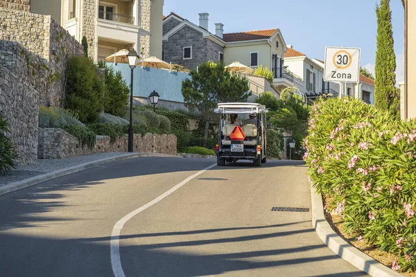 Lustica Körfezi, Karadağ, 14 Haziran 2021: Bir turist arabası (elektrikli araba), güneşli bir yaz gününde turistleri Lustica Körfezi tatil beldesindeki pitoresk bir cadde boyunca götürüyor. Arka plan