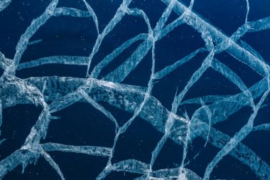 Şeffaf, mavi, berrak buzda sayısız çatlak var. Şaşırtıcı desenler. Yatay olarak. Etkileyici bir masaüstü duvar kağıdı. Baykal Gölü, Rusya