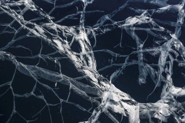 Şeffaf, mavi, berrak buzda sayısız çatlak var. Şaşırtıcı desenler. Yatay olarak. Etkileyici bir masaüstü duvar kağıdı. Baykal Gölü, Rusya