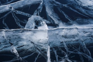 Şeffaf, mavi, berrak buzda sayısız çatlak var. Şaşırtıcı desenler. Yatay olarak. Etkileyici bir masaüstü duvar kağıdı. Baykal Gölü, Rusya