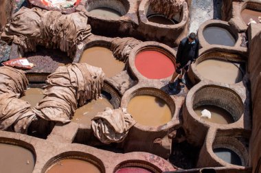 FEZ, Fas - 05 Mayıs 2019: Fez 'deki tabakhanede Wokers. 11. yüzyılda kurulan en büyük ve en ünlü boyama evi. Deri, Fas ve Afrika için renkli boyalı Fez tabakhanelerinin eski kapları..