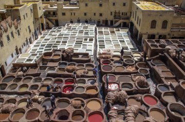 FEZ, Fas - 05 Mayıs 2019: Fez 'deki tabakhanede Wokers. 11. yüzyılda kurulan en büyük ve en ünlü boyama evi. Deri, Fas ve Afrika için renkli boyalı Fez tabakhanelerinin eski kapları..