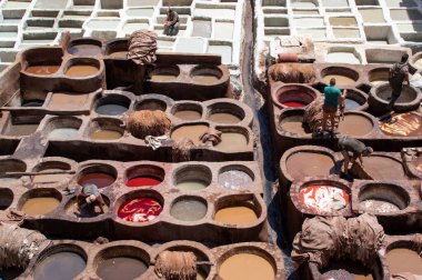 FEZ, Fas - 05 Mayıs 2019: Fez 'deki tabakhanede Wokers. 11. yüzyılda kurulan en büyük ve en ünlü boyama evi. Deri, Fas ve Afrika için renkli boyalı Fez tabakhanelerinin eski kapları..