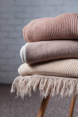 Tahta sandalyenin üzerinde üç renkli yün battaniye var. Kumaş dokusunu kapat.