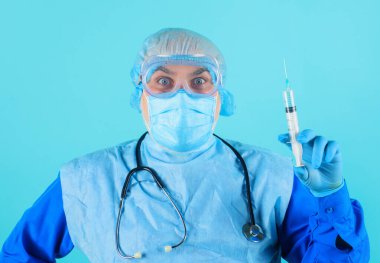 Koruyucu giysili doktor, gözlük ve şırıngalı tıbbi maske. Erkek hemşire aşıyı hazırlıyor..