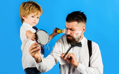 Küçük berber. Babamın asistanıyım. Babalar Günü. Oğlu babası için ayna tutuyor..