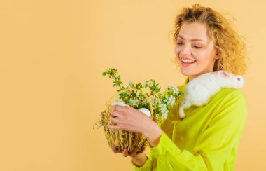Mutlu Paskalyalar. Sepet yumurtalı ve Paskalya tavşanlı gülümseyen kadın..