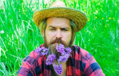 Handsome bearded man with flowers in beard. Man with decorated beard.
