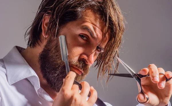 Kapperszaak. Een man met baard, scheermes en schaar. Salon voor mannen. Knappe man met kappersgereedschap. — Stockfoto