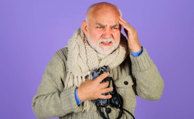 Yüksek tansiyon. Sphygmomanometresi olan yaşlı bir adam. Atardamar tansiyonunu kontrol ediyorum. Şiddetli baş ağrısı.