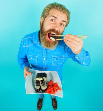 Bir tabak suşi ve turşulu zencefilli sakallı adam. Suşi yiyen adam. Japon yemeği. Deniz yiyeceği.