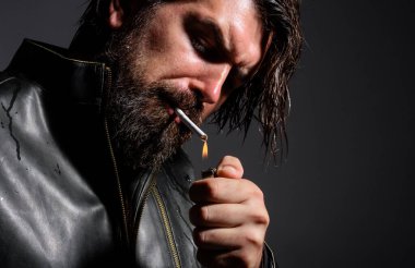 Sigara içen yakışıklı sakallı adam. Çakmak ve sigaralı şık bir hippi. Yakın çekim..