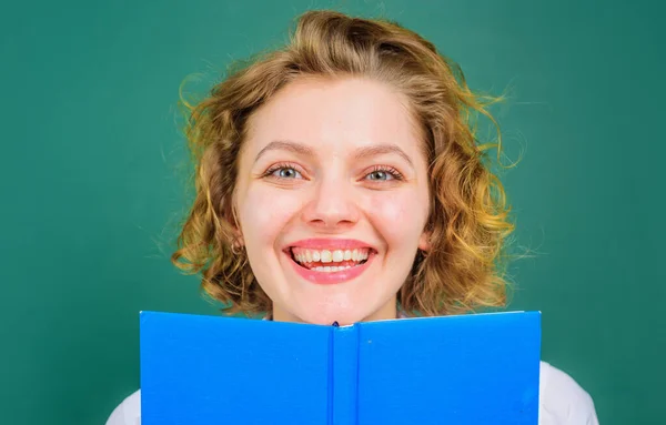 Smiling teacher in classroom. Female lecturer with book. School subjects. Education.