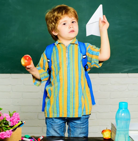 Uczeń w klasie z papierowym samolotem. Dzieciak z podstawówki przy biurku. Edukacja i uczenie się. — Zdjęcie stockowe