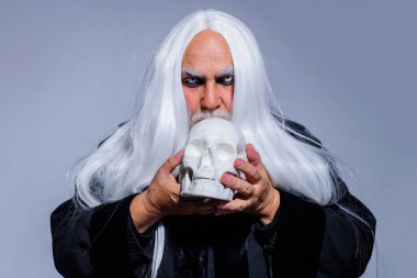 Kafatası büyücüsü. Beyaz gözlü bir vampir adam. Cadılar Bayramı için Büyücü kostümü giymiş sakallı yaşlı bir adam. Korku, Korkunç, Ürkütücü.