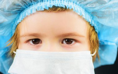 Covid-19 koronavirüs salgınından korunmak için maskeli bir çocuk. Hastalığı önleme. Tıbbi şapkalı ve maskeli küçük bir çocuk. Yakın çekim..