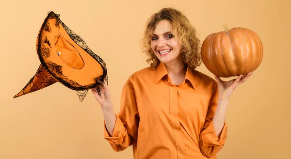 Lachende Halloween heks met pompoen. Gelukkig meisje met magische heksen hoed. Snoep of ik schiet. Halloween tijd. — Stockfoto