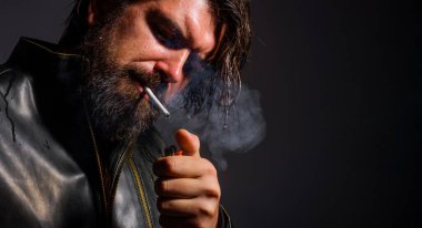 Sigara içen adam. Sakallı adam sigara yakıyor. Kötü alışkanlıklar. Modaya uygun bir adam sigara içiyor. Yakın çekim..