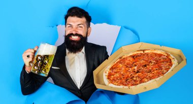 Lezzetli pizza ve birayla sakallı adam kağıt delikten bakıyor. Lezzetli pizza ve soğuk biranın tadını çıkar.