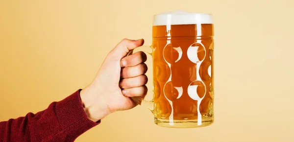 Oktoberfest. Man hand with glass of draft beer with foam. Fresh cold beer in glass in hand. Beer pub.