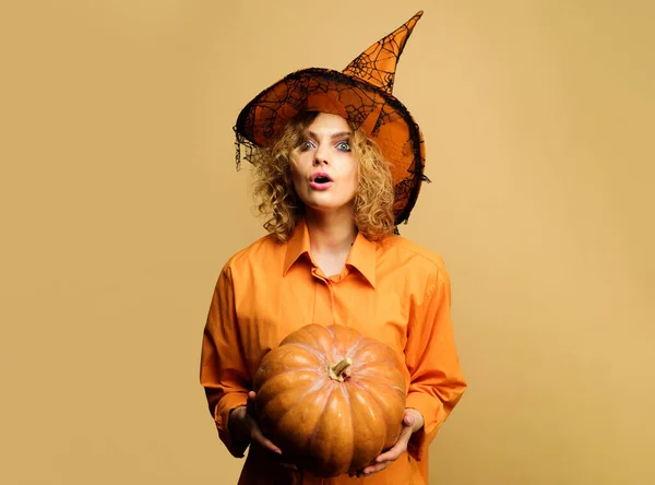 Mujer sorprendida en sombrero de bruja con calabaza. Chica en traje de Halloween con jack-o-linterna. Halloween vacaciones. —  Fotos de Stock
