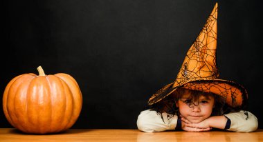 Cadılar Bayramı kostümlü şirin çocuk ve balkabaklı cadı şapkası. Cadılar Bayramı sonbahar tatili.