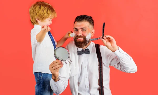 儿子和父亲在理发店。在理发店里做衣服爸爸的助手父亲节。小理发师理发店的广告. — 图库照片