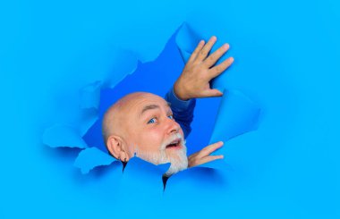 Kağıt delikten bakan, gülümseyen sakallı adam. Mavi lensli yakışıklı adam kağıt duvarda delik açıyor. Erkek kafası delikten bakıyor. Mevsimlik satış ve indirim. Reklam için boşluk kopyala