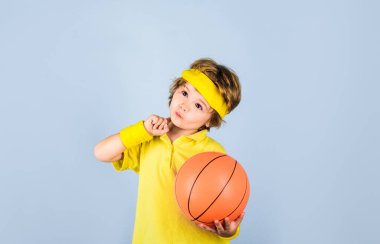 Küçük basketbolcu basketbol topunu tutuyor. Sarı tişörtlü, basketbolcu şirin çocuk. Spor çocuğu. Çocuk basketbol oynuyor. Spor, hobi ve sağlıklı yaşam tarzı. Çocuklar için etkinlik ve spor