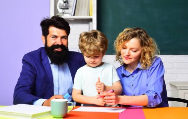 Okula dönelim. İlkokul öğrencisi özel öğretmenlerden ders alıyor. Ödev yapan çocuklara yardım eden birkaç öğretmen. Eğitim, öğrenme. Sınıfta masasında okul çocuğu olan bir erkek ve kadın öğretmen.