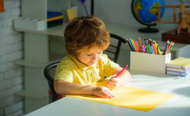 Küçük çocuk ilkokul için ödev yapıyor. Okula dönelim. Sınıfta ödev yazan konsantre bir öğrenci. Masada oturan sevimli okul çocuğu çizimi. Çocuk yazmayı öğreniyor. Okul malzemeleri.