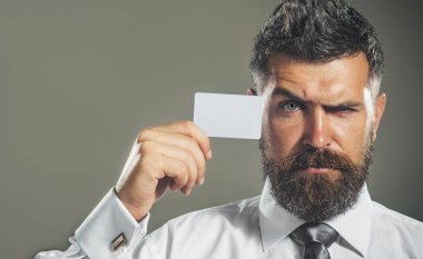 Kredi kartı ya da banka kartı gösteren yakışıklı bir iş adamı. Nakitsiz ödeme. Finans, e-para ve işlemler. Resmi olarak sakallı ve banka kartı takan ciddi bir adam. Reklam bankacılığı hizmetleri için boşluk kopyala